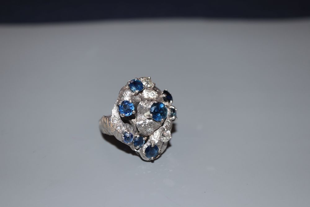 A 1970s? textured 18ct, sapphire and diamond cluster dress ring, in a raised setting, size P, gross 14.7 grams.